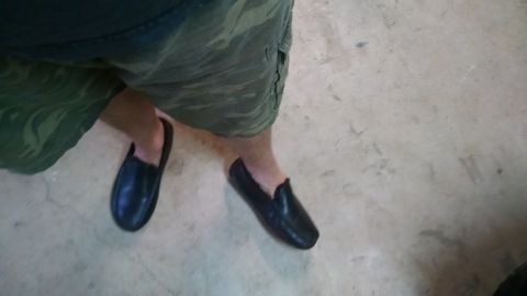 1985 Jeep CJ7 - The image shows a person's legs wearing camouflage shorts and black slip-on shoes, standing on a concrete floor. The vehicle is not visible…