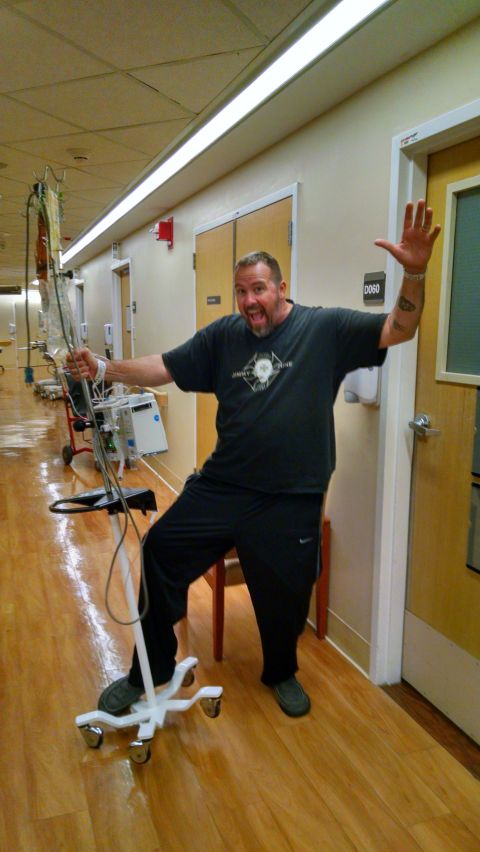 1985 Jeep CJ7 - A man in a hospital gown and sweatpants poses with an IV pole in a hospital hallway.