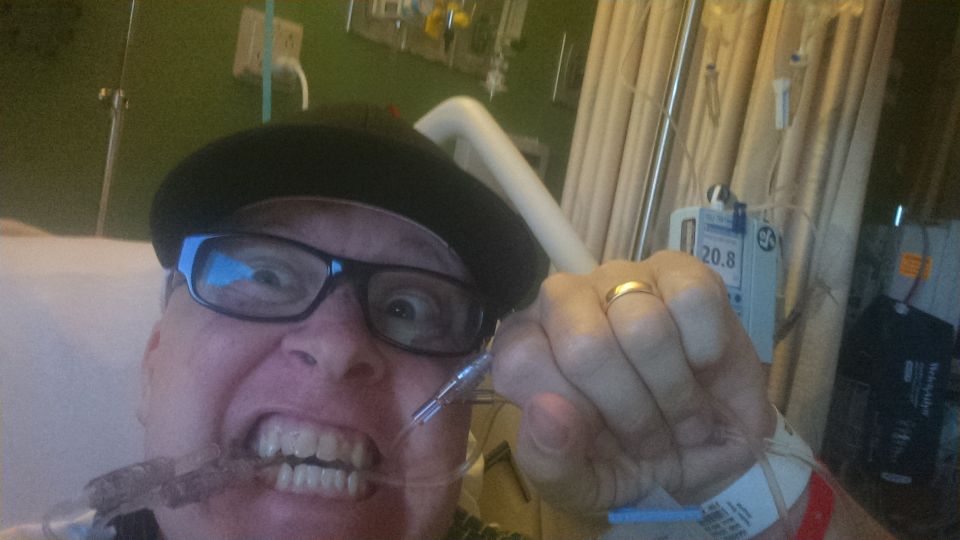 Person in hospital bed with nasal cannula and IV pump.