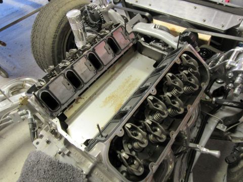 Disassembled V8 engine with rocker arms and valve springs visible, installed in a vehicle chassis.