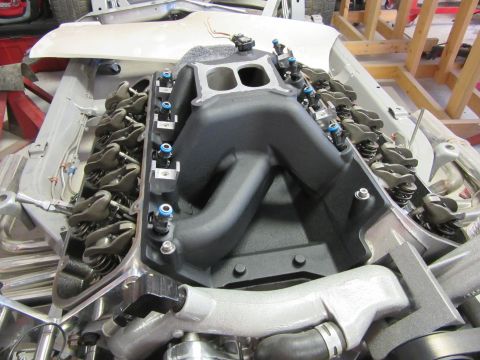 Close-up of a V8 engine with black intake manifold and silver valve covers.