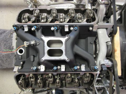 V8 engine with black intake manifold, aluminum valve covers, rocker arms, and fuel injectors.