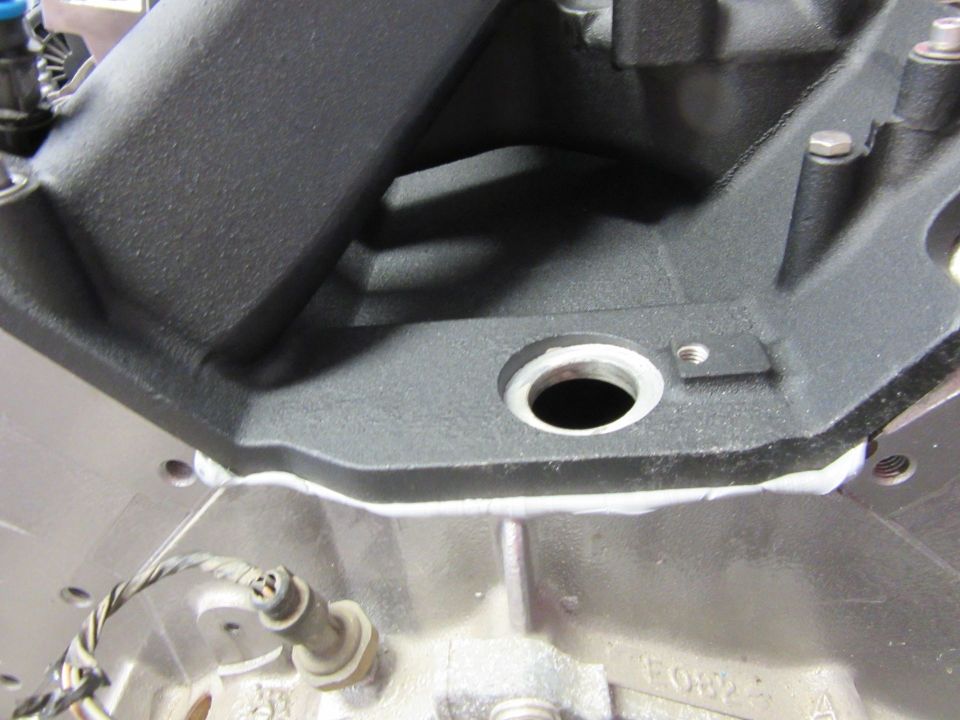 Close-up of engine intake manifold bolted to engine block with sealant.