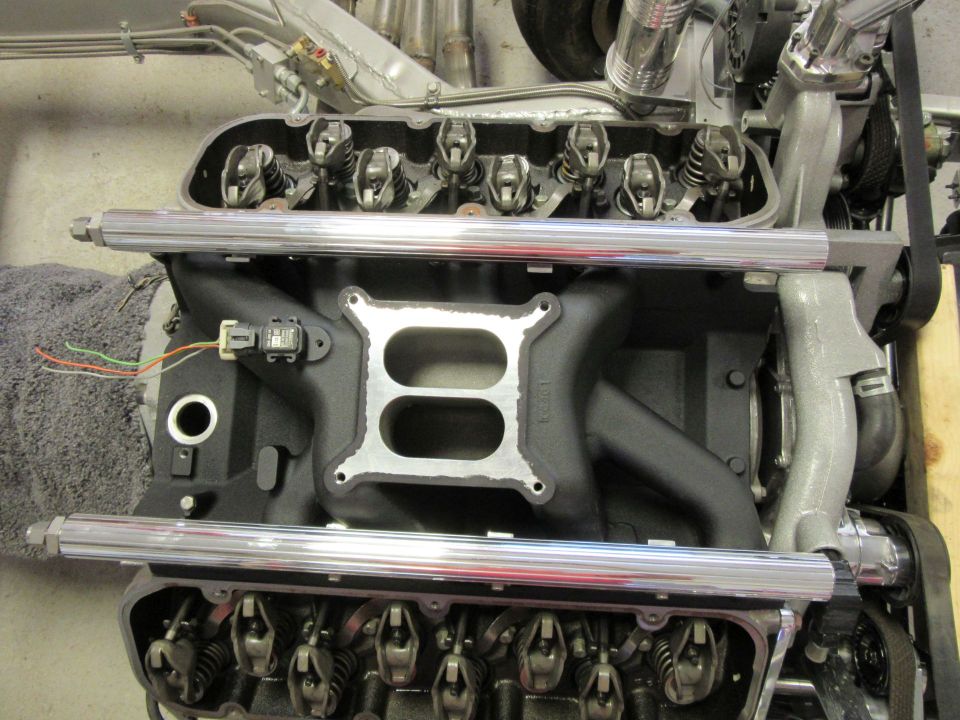 Close-up of a V8 engine intake manifold with chrome fuel rails.