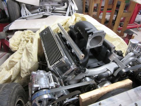 Chrome engine with Edelbrock intake and Ford valve cover, partially covered.