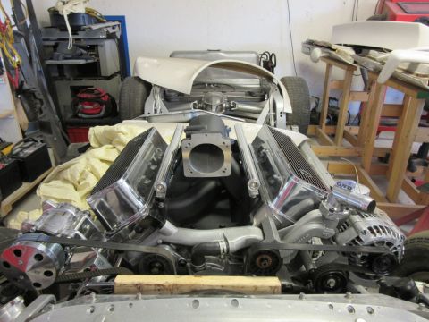 Custom V8 engine with chrome valve covers and intake in a project car chassis.
