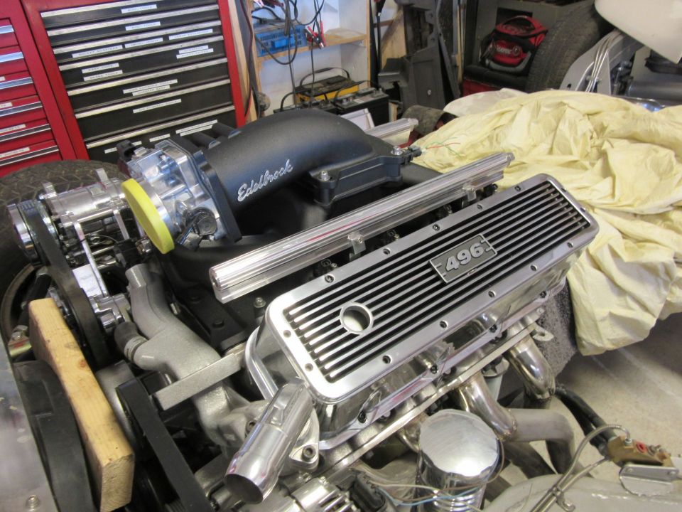 Close-up of a V8 engine with chrome valve covers labeled "496" and an Edelbrock intake.