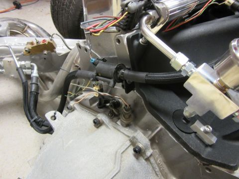 Close-up of engine bay with hoses, wiring, and metal components.