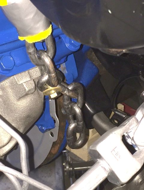 1978 Ford Bronco - A close-up view shows a metal chain attached to a blue engine component, with a bolt and washer securing the chain links. The chain appears…