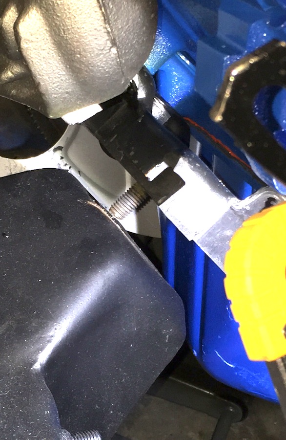 Close-up of a bolt on a black part, with blue metal and yellow plastic.