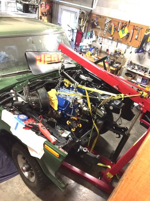 1978 Ford Bronco - A green Ford Bronco is in a garage with its hood open, undergoing engine work. An engine hoist is supporting the engine as it is being work…