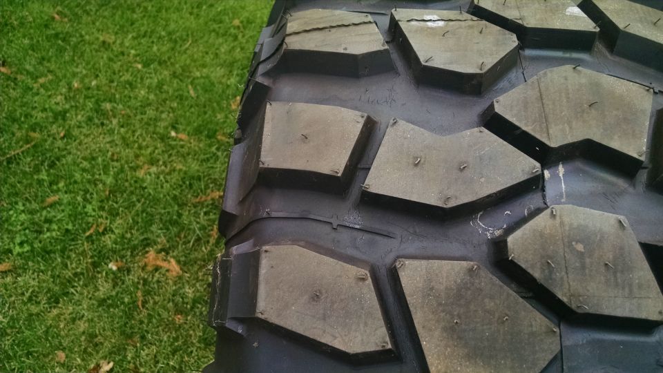 Close-up of a studded off-road tire tread on grass.
