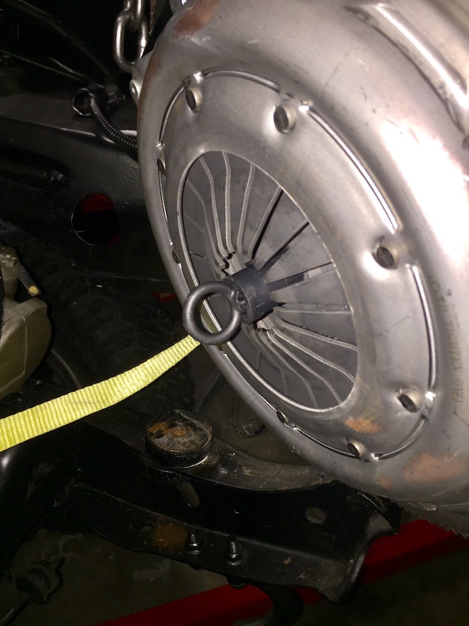 Vehicle clutch assembly with a yellow strap and chain hoist.