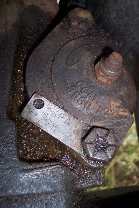 1973 Ford F-250 - A close-up view of a greasy, cast-iron automotive part with stamped lettering and a metal tag. The lettering on the part reads "CCAR 3580-A…
