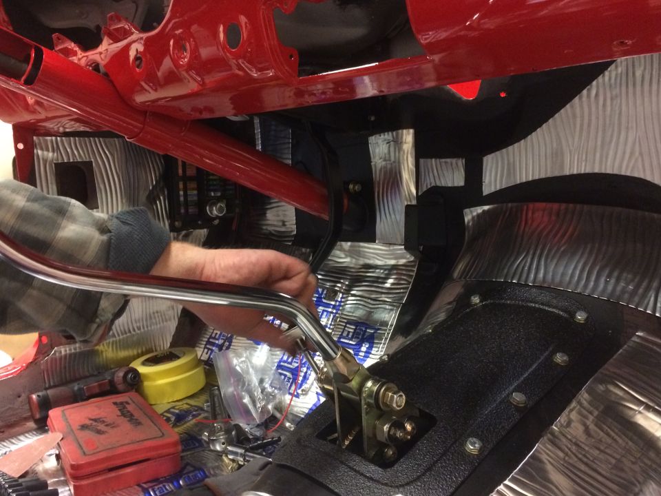 Hands working on car interior with red frame and sound deadening material.