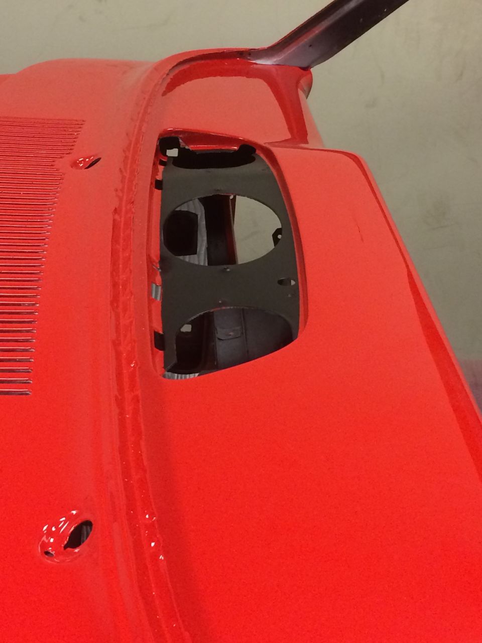 Close-up of a bright red car exterior with a ribbed section and cutouts.