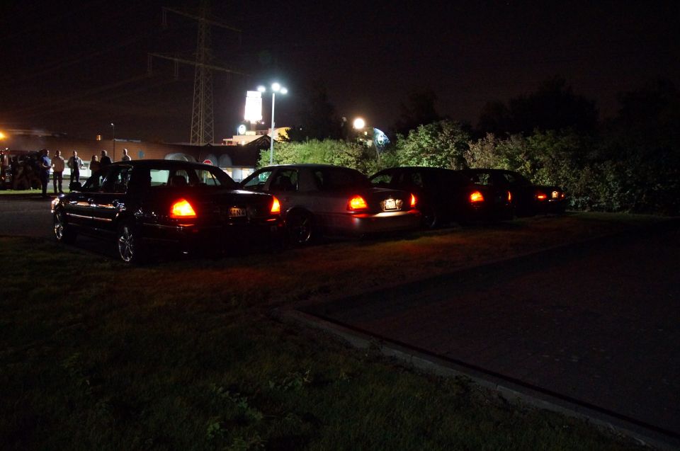 Four sedans parked at night with brake lights on.