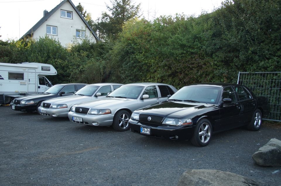 Black Mercury Marauder and three silver sedans parked in a lot.