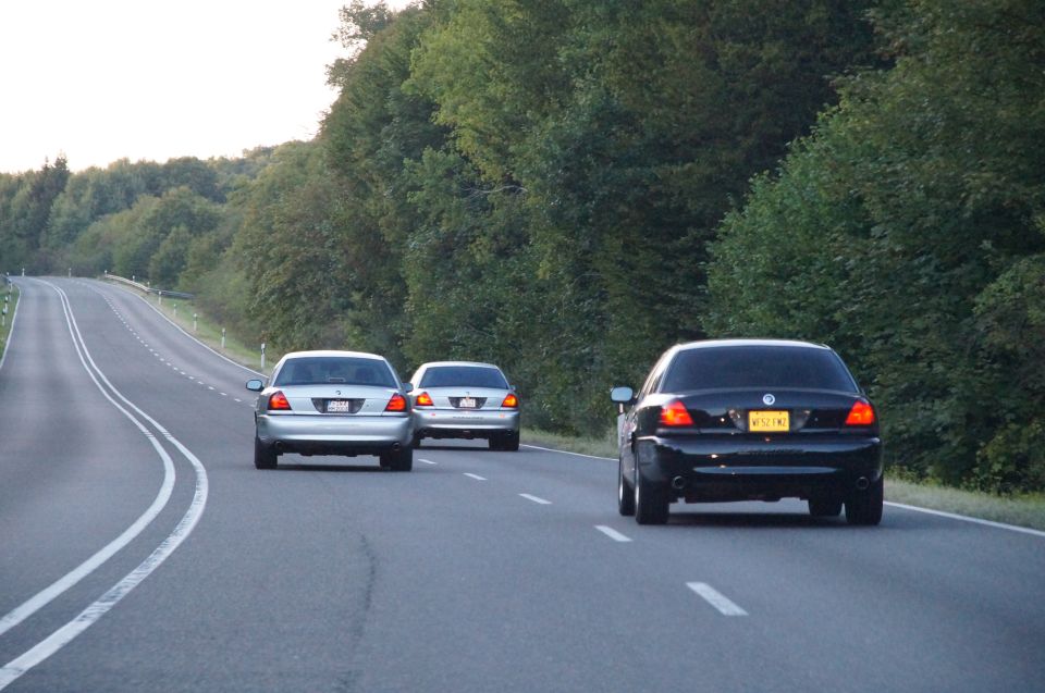 Three sedans, including a black 2003 Mercury Marauder, drive on a highway