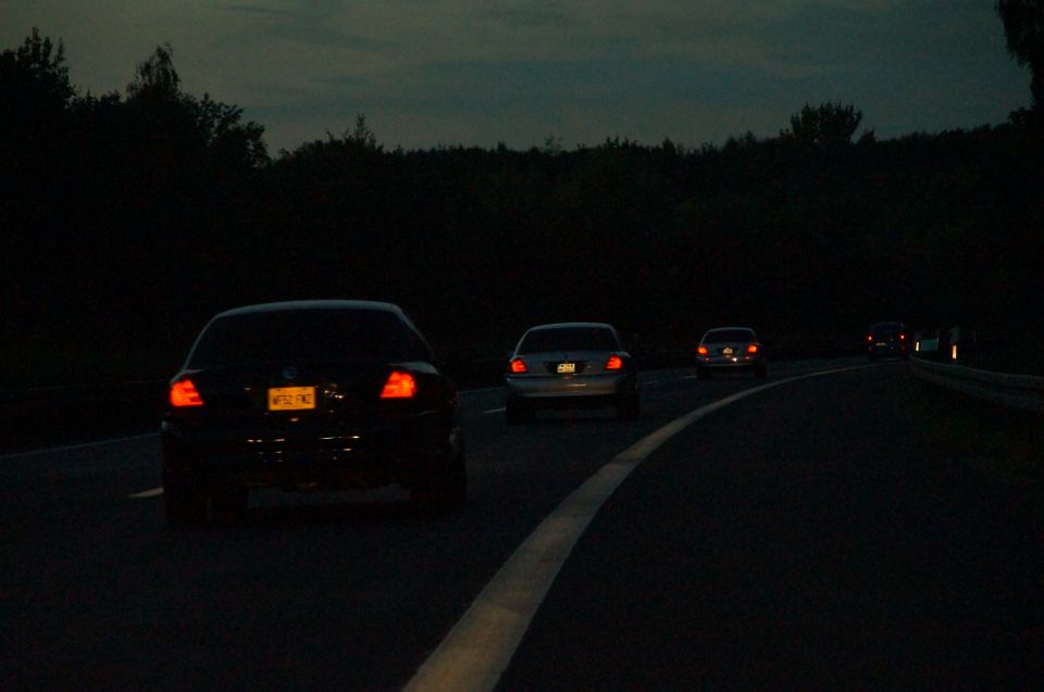 Black sedan's rear view with illuminated taillights and license plate at dusk