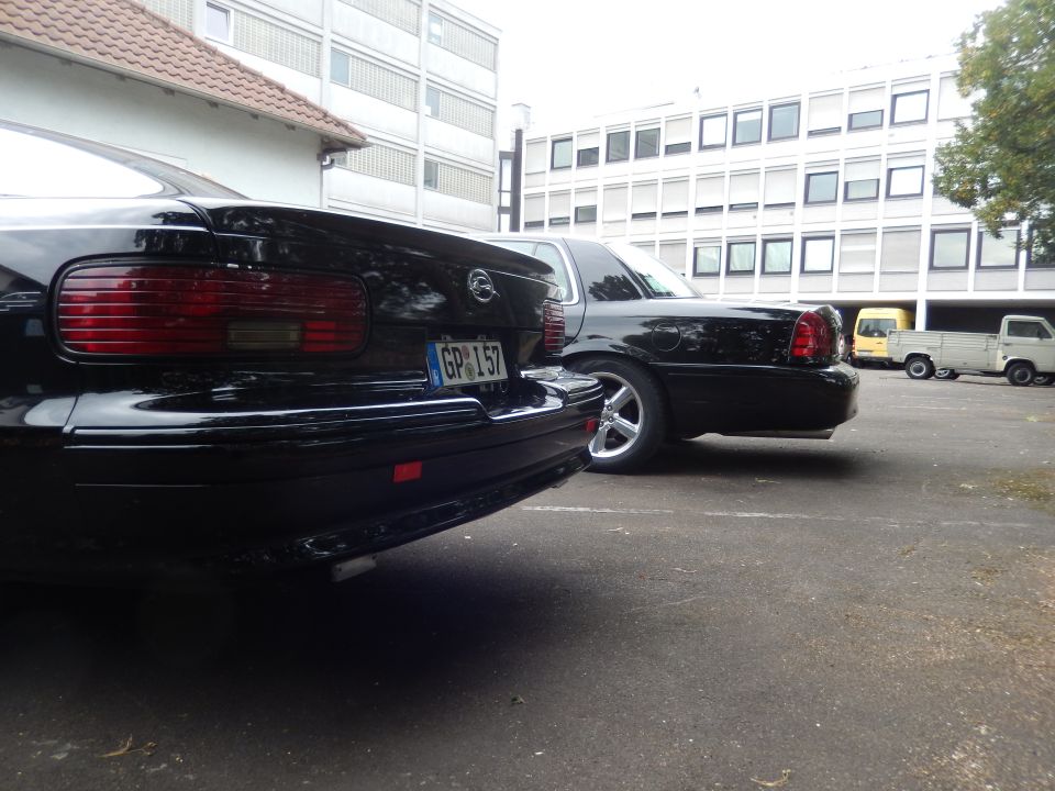 Rear view of a black sedan, license plate GP 157, parked next to another black sedan