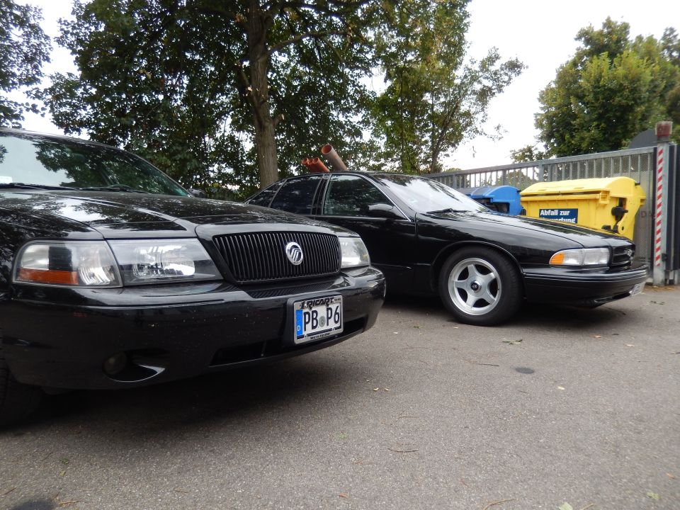 Front of a black Mercury Marauder next to another black sedan