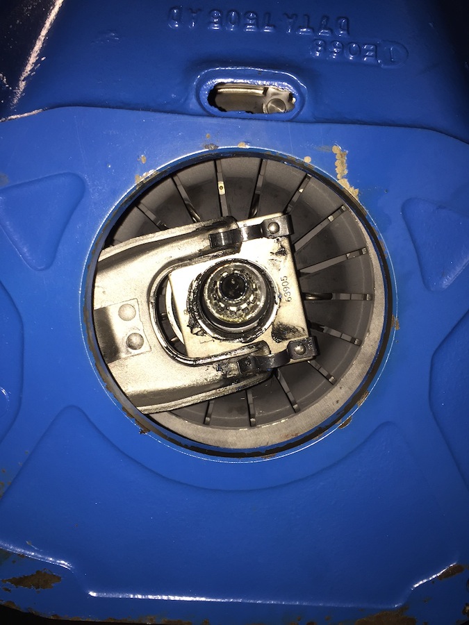 Close-up of a blue metal housing with a circular opening revealing internal mechanical components, possibly a clutch or brake assembly
