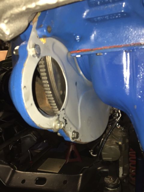 1978 Ford Bronco - Close-up view of a blue engine bell housing with a silver adapter plate and visible flywheel teeth.