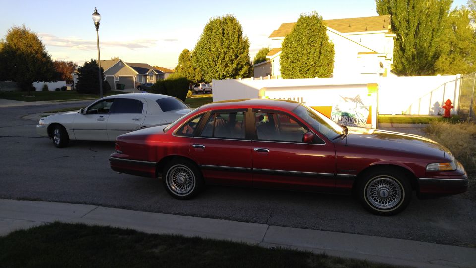 Red sedan parked on street, white sedan behind it. Both are sedans