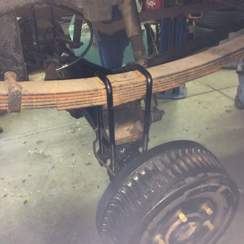 1962 Chevrolet Suburban - The rear suspension of a vehicle, showing leaf springs and a drum brake assembly.