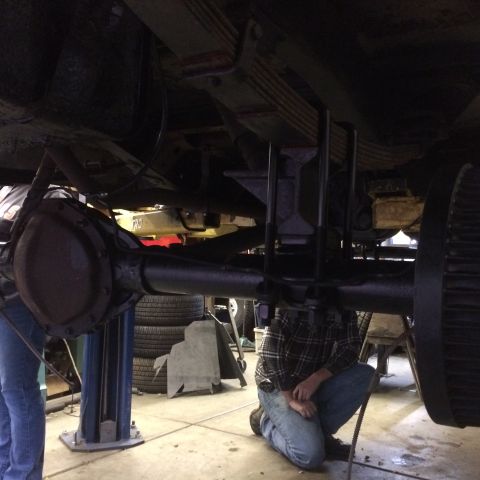 1962 Chevrolet Suburban - Mechanics work on the rear axle assembly of a vehicle, likely during a suspension modification or repair.
