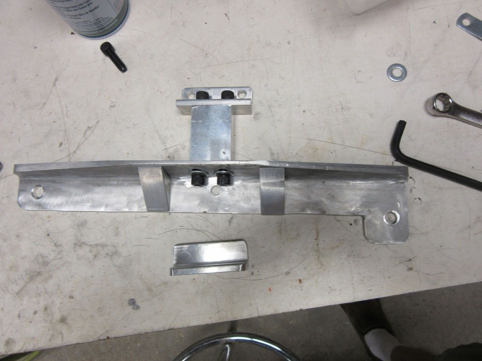 Fabricated aluminum bracket part lying on a workbench with hand tools