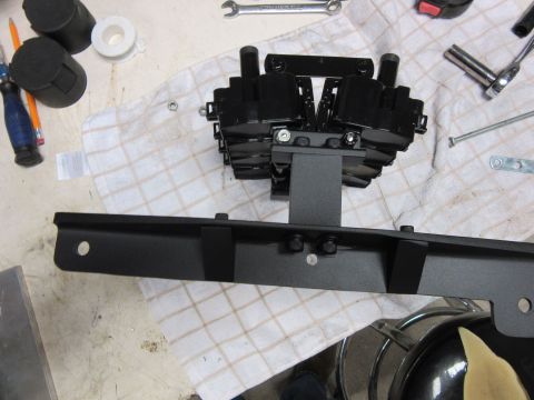 Black engine part assembly with metal bracket on a checkered cloth