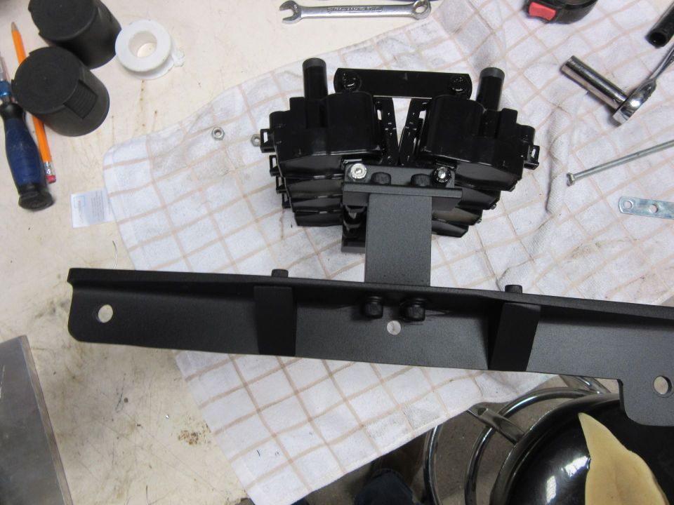 Black engine part assembly with metal bracket on a checkered cloth