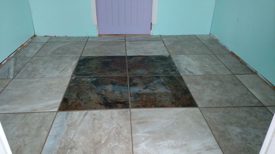 Tiled floor with a darker square in the center, light blue walls, and a purple door