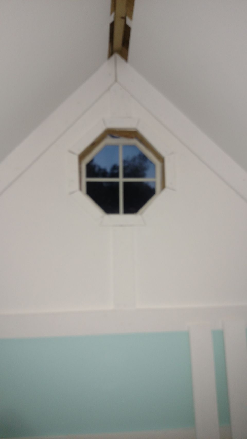 Octagonal window in a white playhouse wall