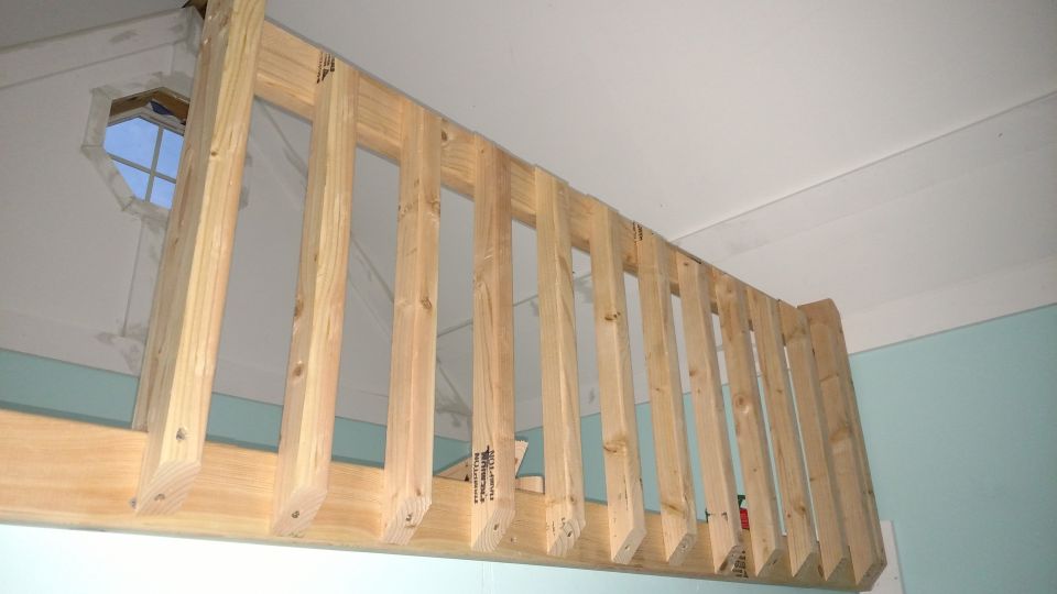 Wooden railing construction with a hexagonal window visible in the background