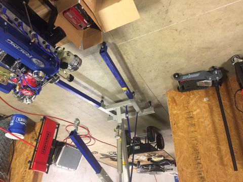 1982 Ford Bronco - A blue Ford Racing engine is suspended from an engine hoist in a garage setting.