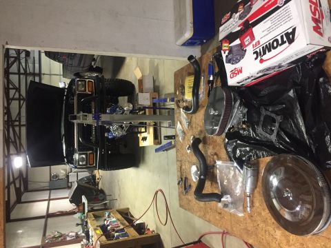 1982 Ford Bronco - Vehicle on lift in garage with engine parts laid out on workbench.