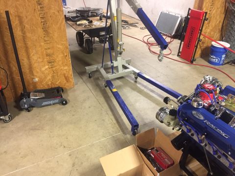 1982 Ford Bronco - A blue Ford Racing engine is prepared for installation in a garage, surrounded by automotive equipment.