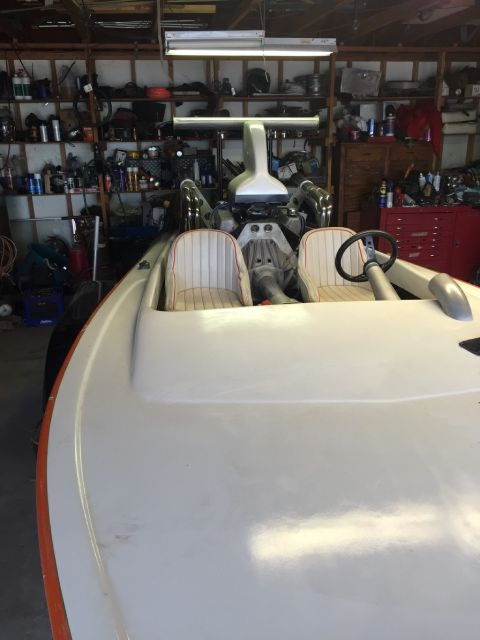 1970 Ford Five Hundred - A white boat with orange trim is parked inside a garage, showing its interior and engine components.