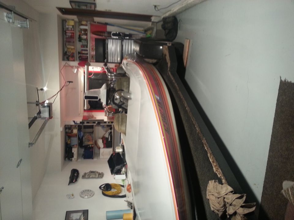 Car interior with white seats and dashboard, garage shelves with tools and supplies in background