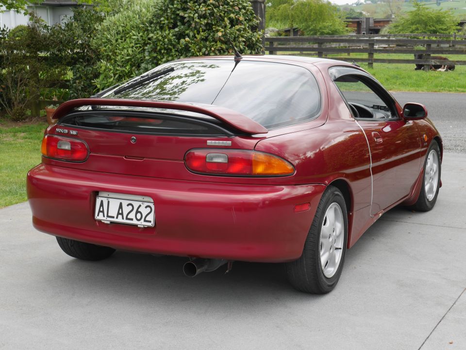 Red 1993 Mazda MX-3 rear view with spoiler and license plate ALA262