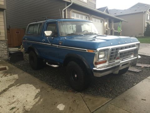 1979 Ford Bronco - This blue Ford Bronco is parked in a driveway, showing its front 3/4 view.