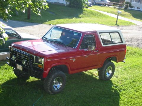 1981 Ford Bronco - This red Ford Bronco is parked on a grassy lawn with a white removable top.