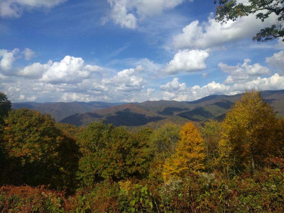 Mountain landscape with trees in autumn colors under a cloudy blue sky
