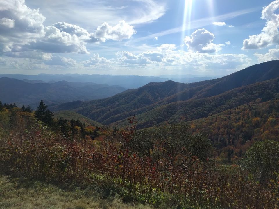 Mountain range with trees and clouds under a bright sun