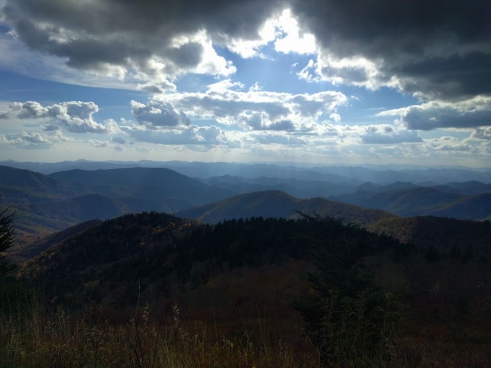 Mountain range under a cloudy sky with sunbeams breaking through