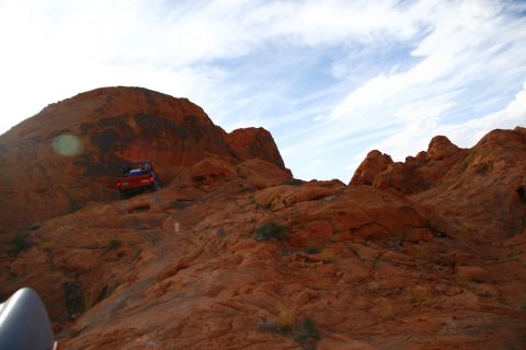 1979 Ford Bronco - A red 1979 Ford Bronco is shown driving up a steep, rocky, orange desert terrain.