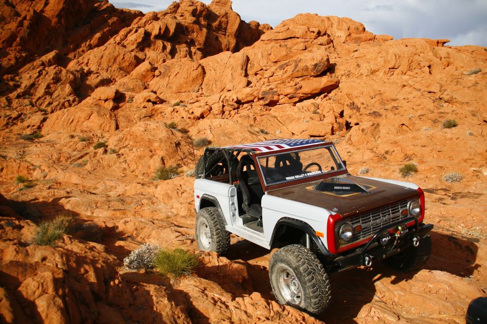 White 1979 Ford Bronco with American flag roof in a desert landscape.